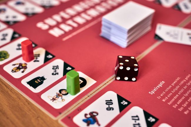 Exemplarische Spielsituation des SMM: Spielbrett mit Figuren, Ereigniskarten und Würfel.